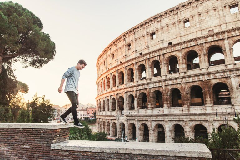 A man thoughtfully walking in front of a historic Roman site, symbolizing exploration and discovery of personal histories and family legacies.