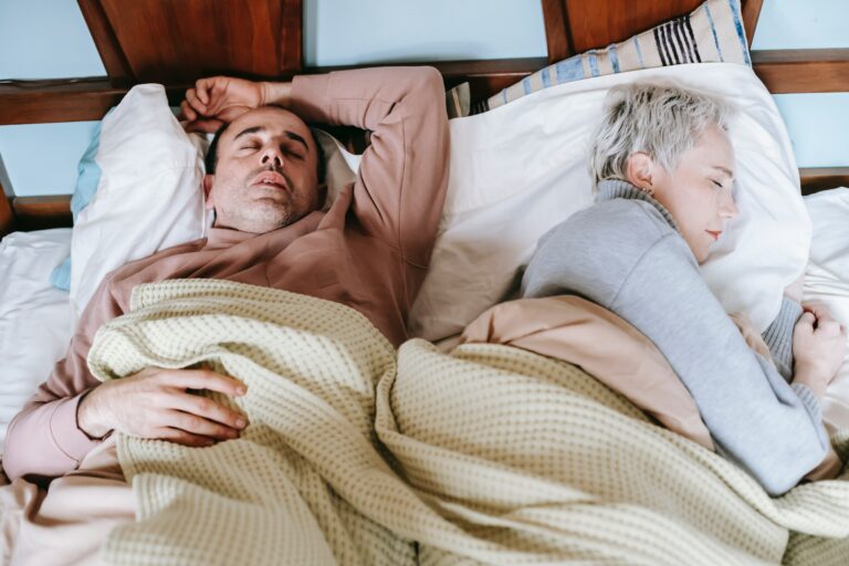 Middle-aged couple peacefully sleeping, illustrating the restorative and protective benefits of deep sleep for brain health, especially in relation to Alzheimer's disease prevention.